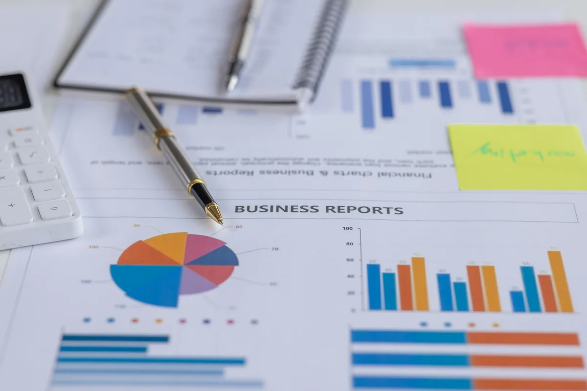 Business reports, charts, a pen and calculator arranged on a desk